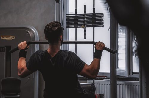 Back view of a man exercising with lat pulldown machine in the gym.